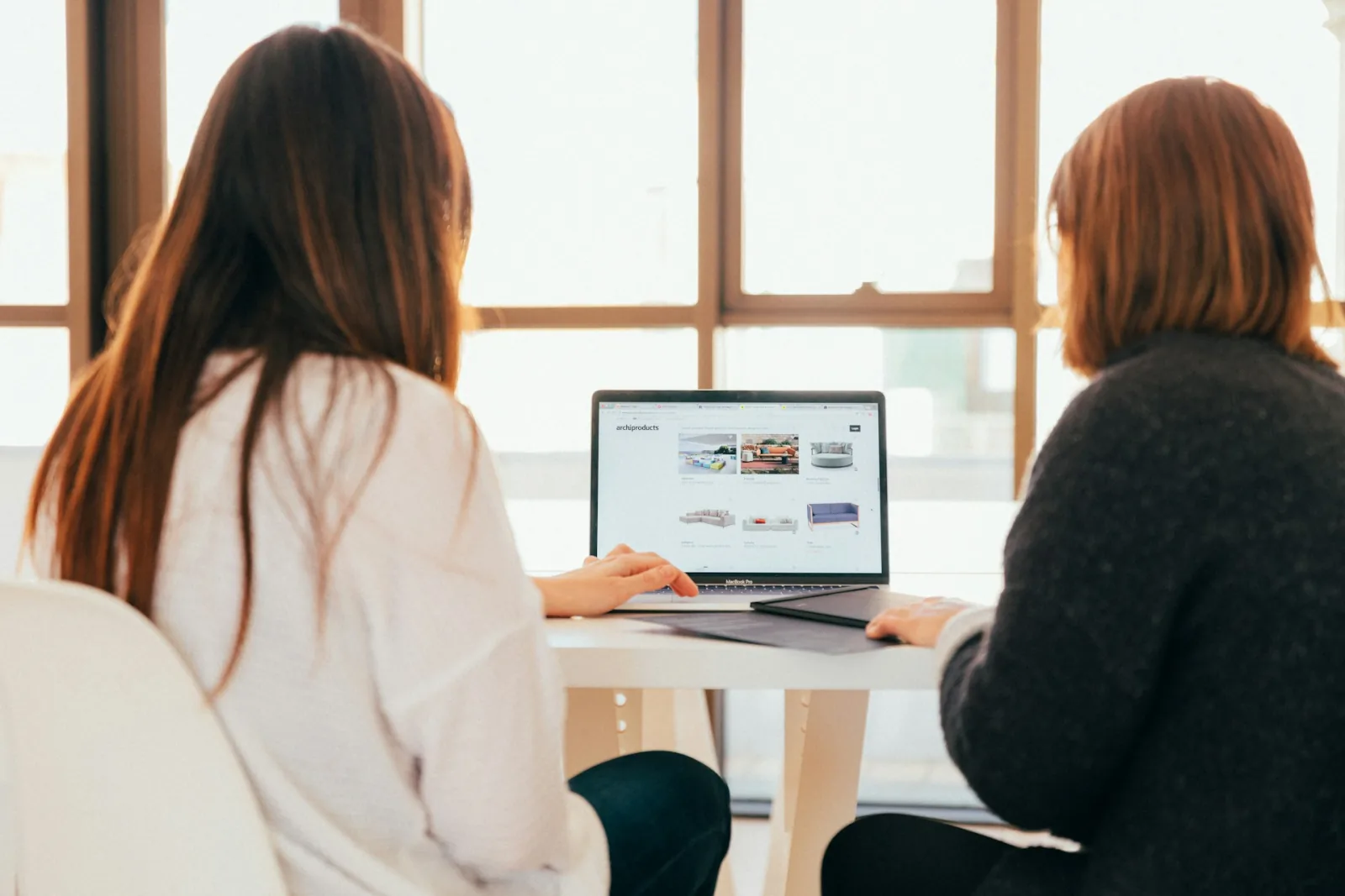 two women talking while looking at laptop computer 