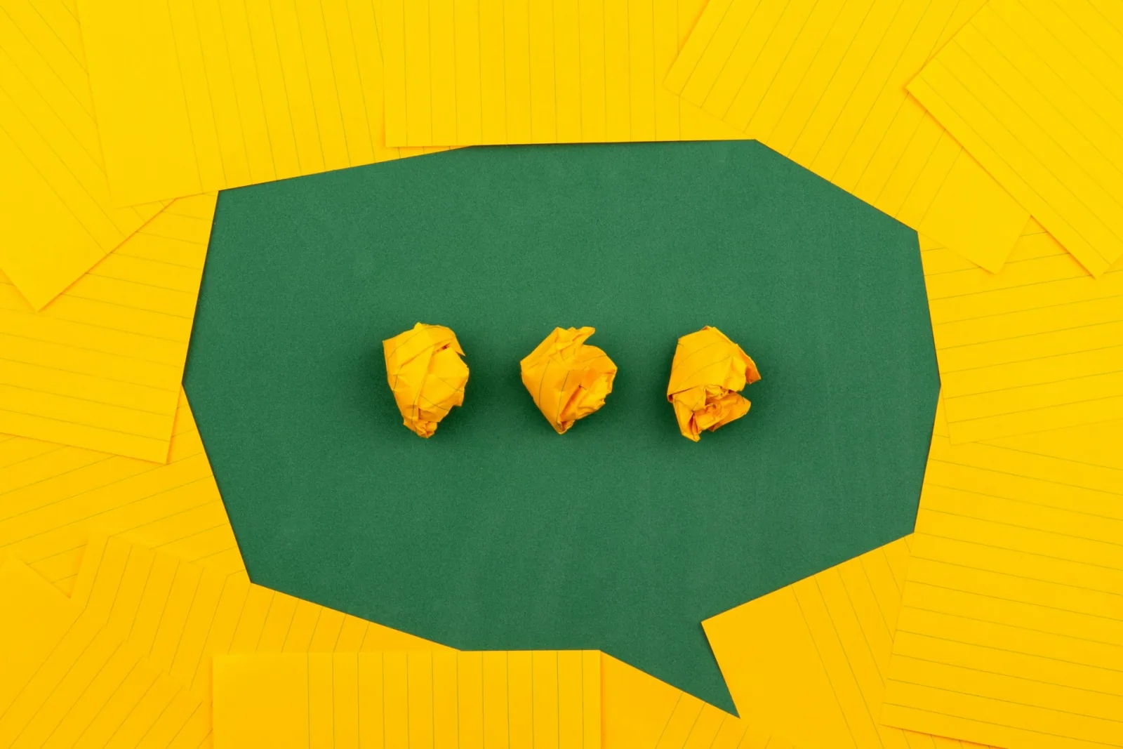 Why Visual Design Makes Content Marketing Effective image Orange sheets of paper lie on a green school board and form a chat bubble with three crumpled papers.