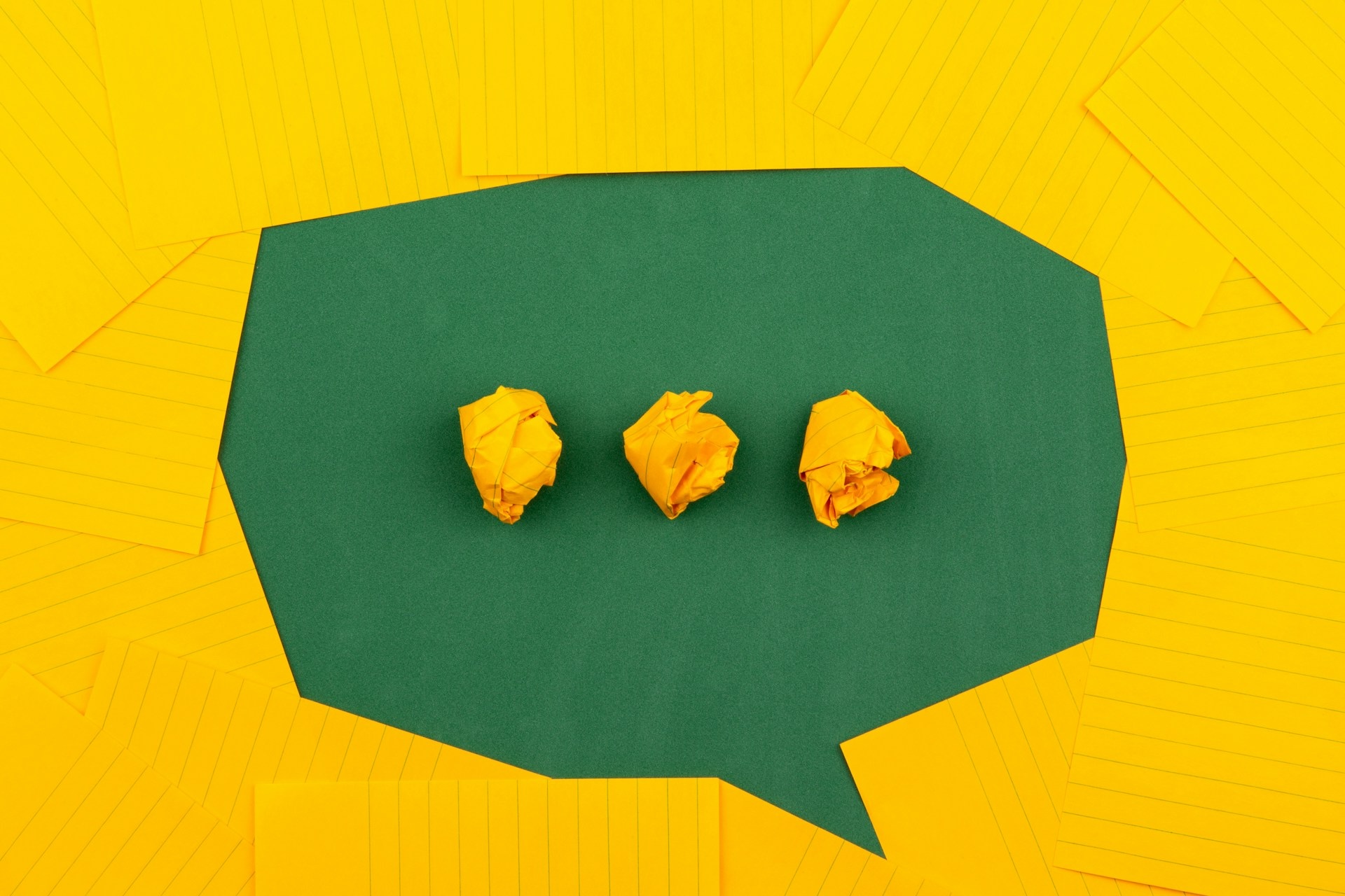 Why Visual Design Makes Content Marketing Effective image Orange sheets of paper lie on a green school board and form a chat bubble with three crumpled papers.