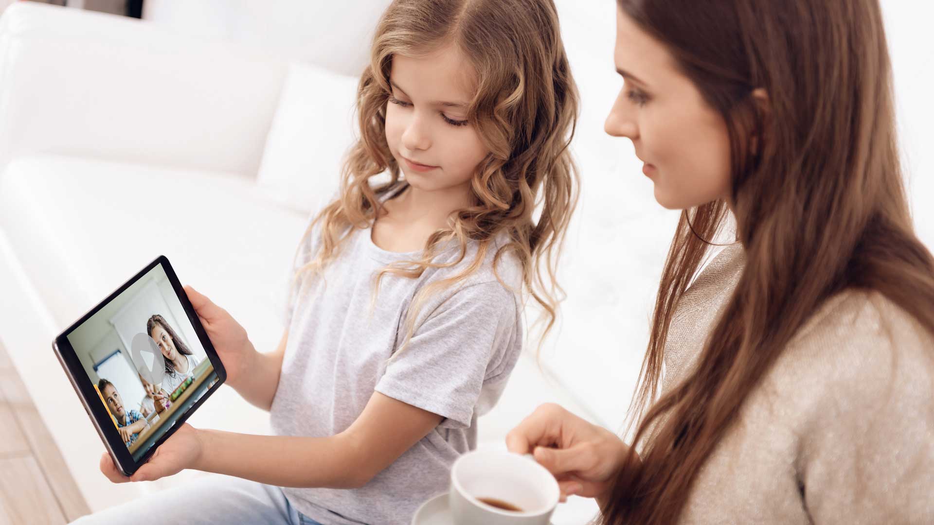 Private School Ad Strategies: Attract Prospective Parents image Girl and mother check out Greenfield Academy video on iPad.